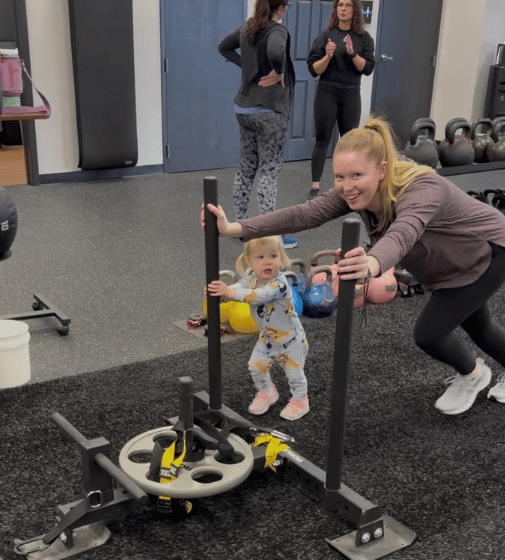 mom is pushing a sled for conditioning at ROI Strength gym in Midlothian VA